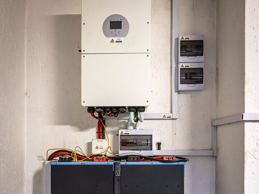 A wall-mounted solar inverter connected to a home battery storage unit